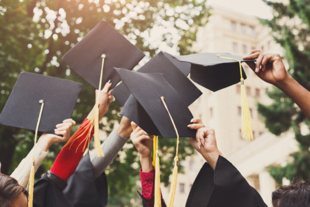 Group of college graduates holding up their graduation caps