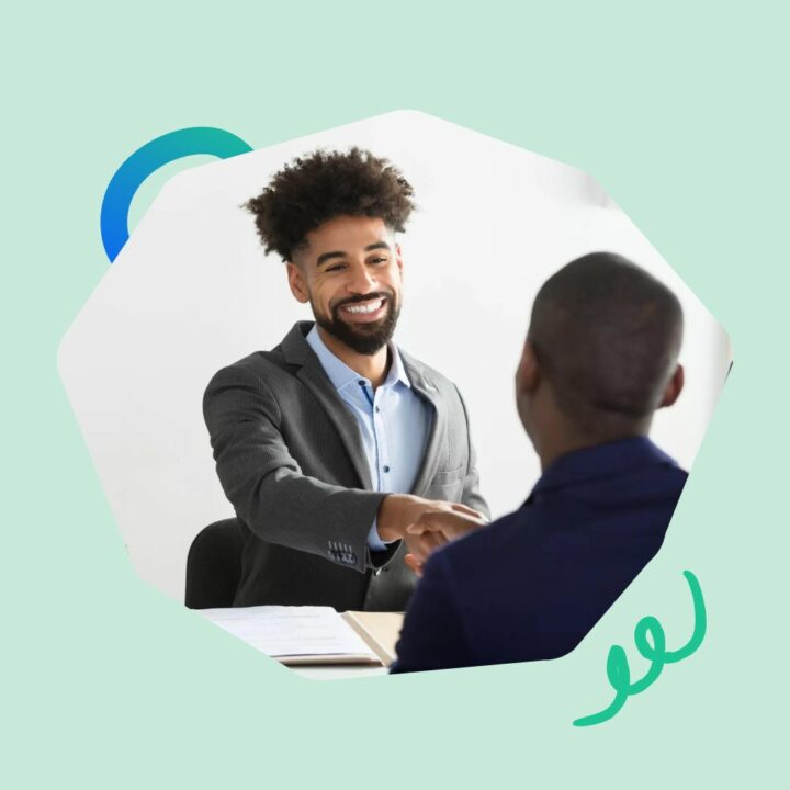 Two male professionals shaking hands across a desk