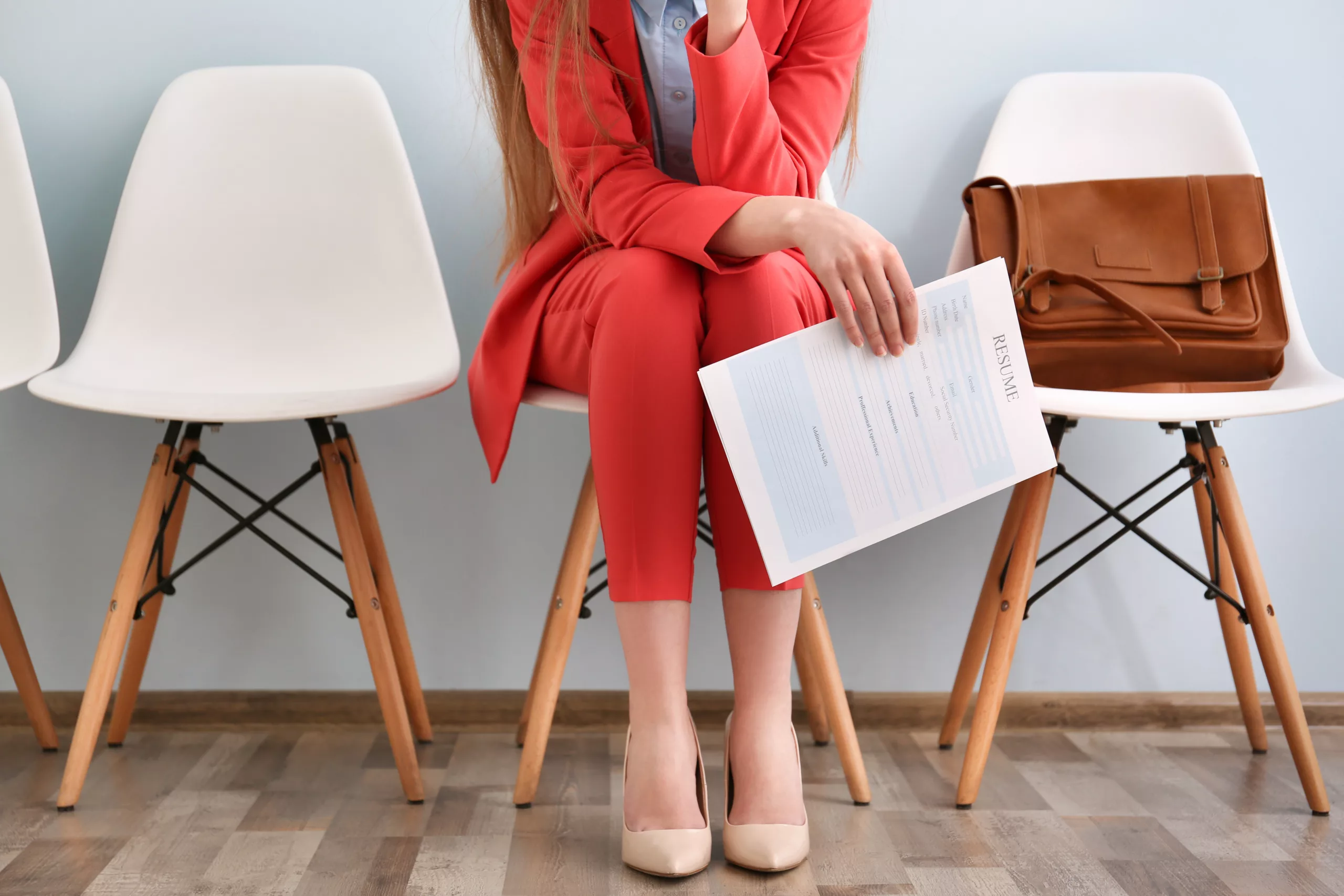 Female professional waiting in a chair for an interview and holding her resume