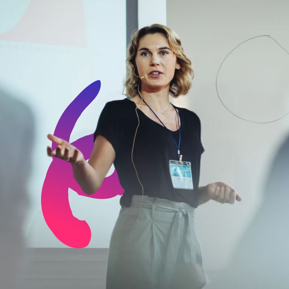 Woman professional standing on stage with a microphone in front of a presentation speaking to an audience