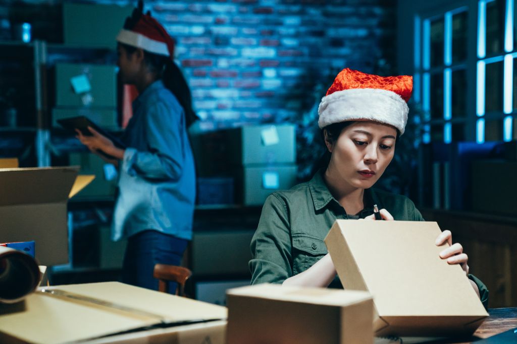 Two women in warehouse working to pack parcels for the holiday season