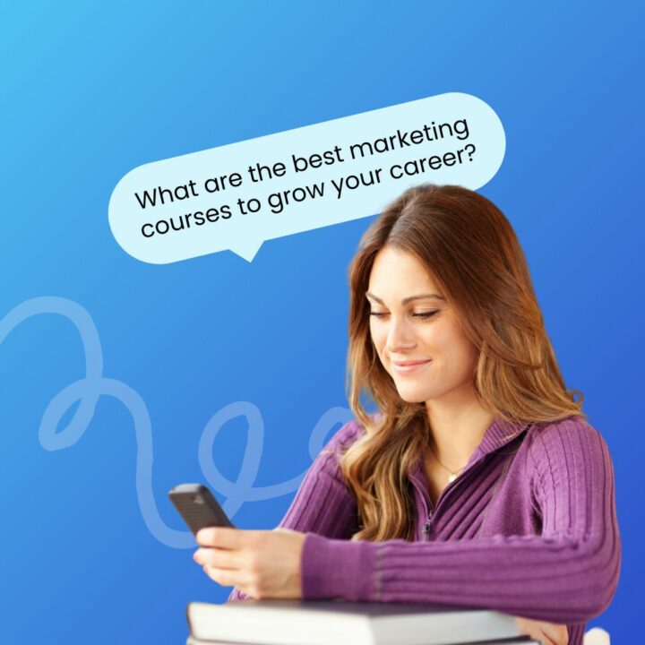 A young woman with long brown hair, wearing a purple sweater, sits at a table with books in front of her, looking at her phone with a smile. A speech bubble above her head reads, 'What are the best marketing courses to grow your career?