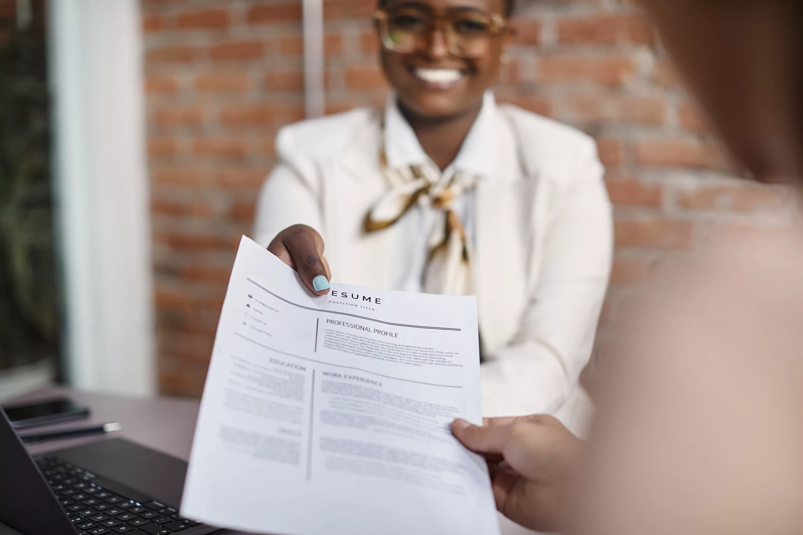 Woman professional handing a resume in a professional format to her interviewer in a modern office