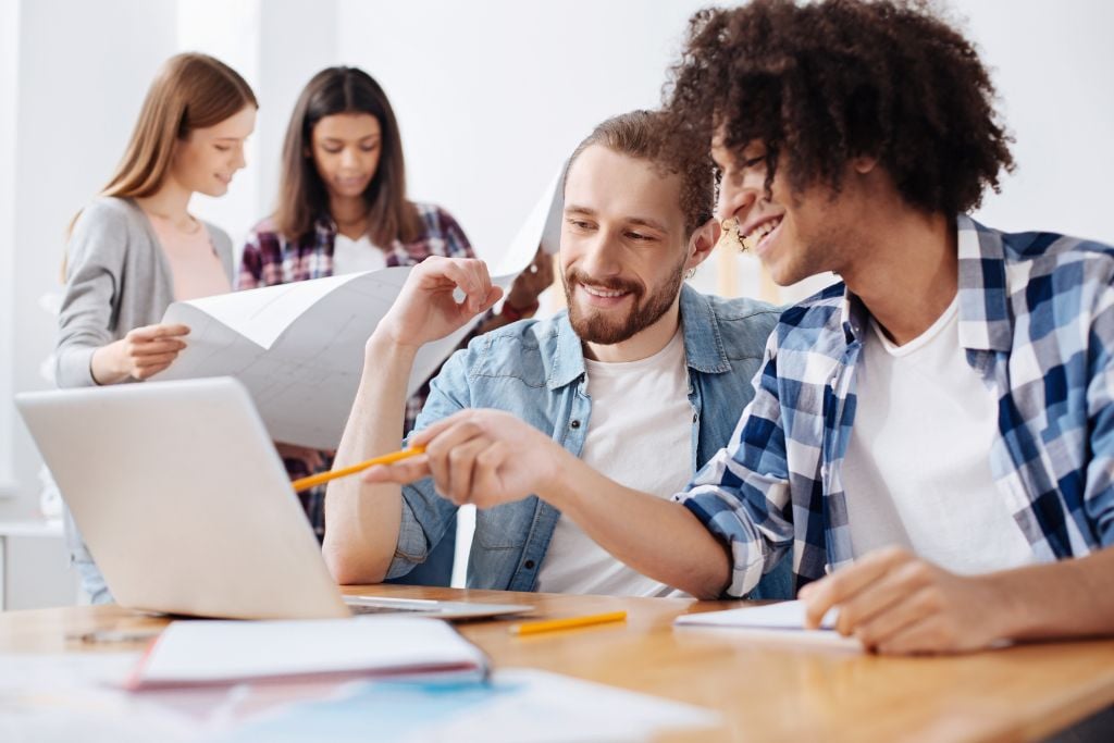 Two young male professionals showing sign of excellent soft skills when discussing a project at work