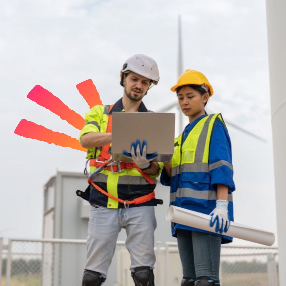 Male and female public utilities engineer in uniform with helmet safety using laptop discussing inspection and maintenance of wind turbine in wind farm to generate electrical energy.