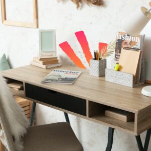 Organized desk with magazines, books, and stationery neatly arranged, featuring a modern lamp and a stylish, minimalist decor