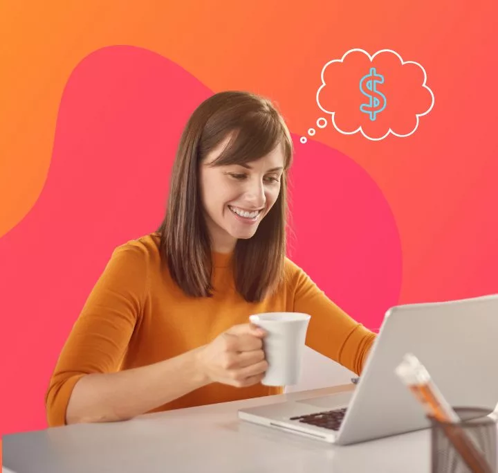 Young entry-level female professional wearing an orange long sleeve shirt holding a white mug sitting at a white desk behind a laptop at an office with a money symbol in a thought bubble