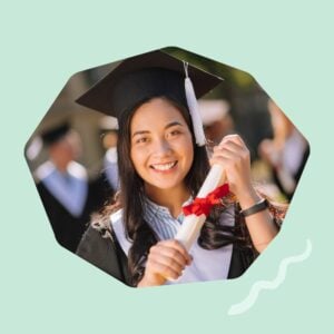 A smiling female graduate in a cap and gown holds a business degree diploma tied with a red ribbon.