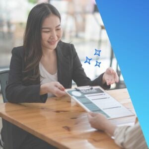 Smiling female professional in a blazer handing over a resume during a job interview